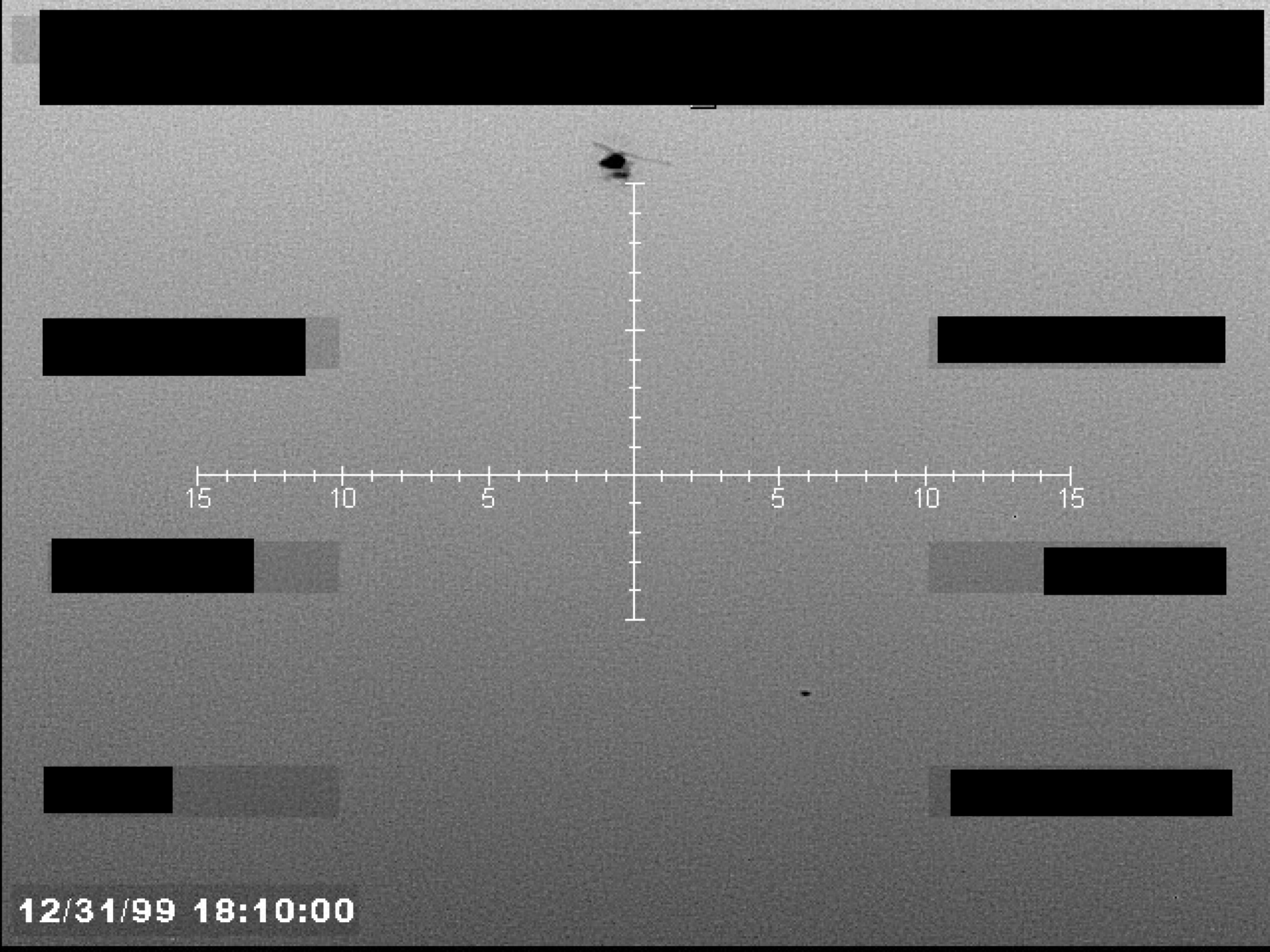 Sensor display, possibly FLIR, showing a targeting crosshair with a small, dark, unidentified object near the center. A timestamp is visible in the lower-left corner.