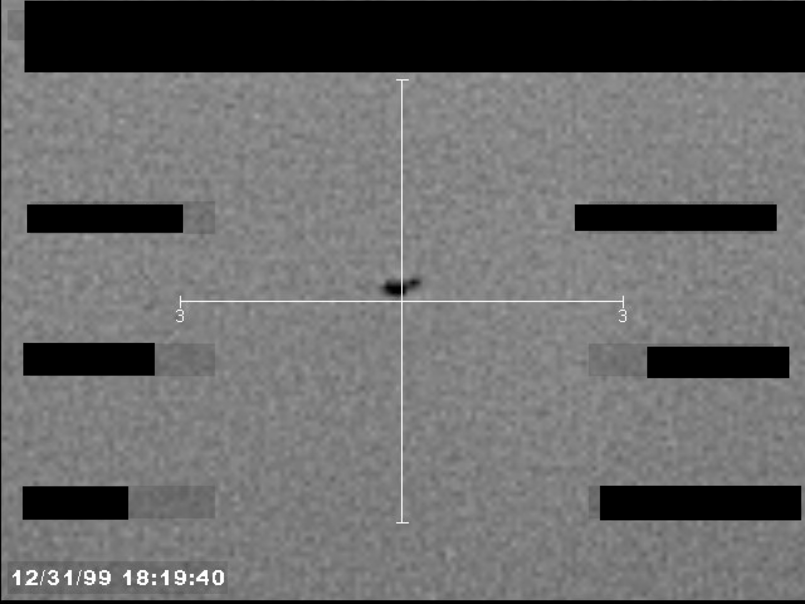 Sensor footage frame showing a small, dark object at the center of a crosshair.