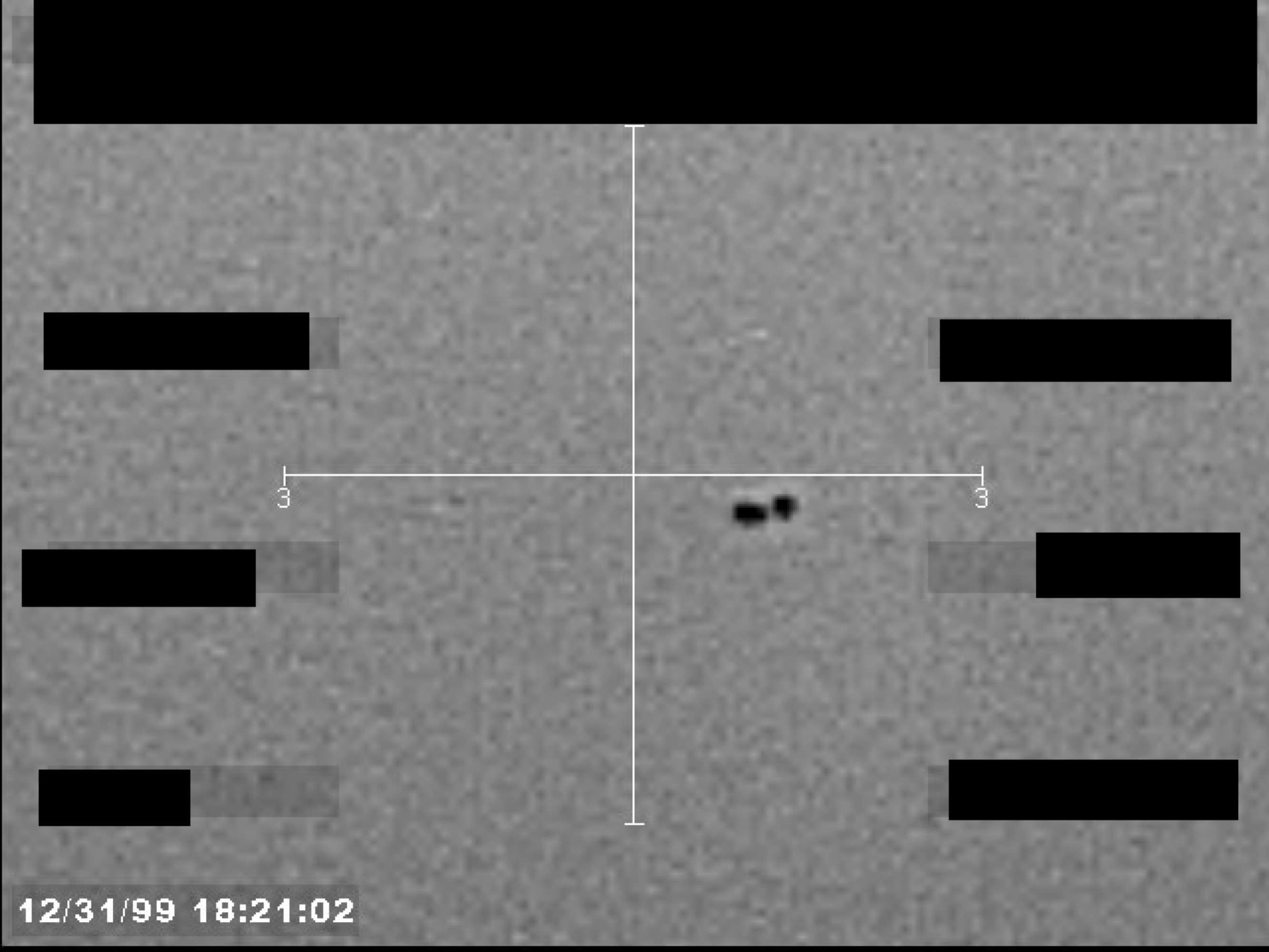 Sensor display showing two small, dark objects near a central crosshair, with a timestamp and redacted data fields.