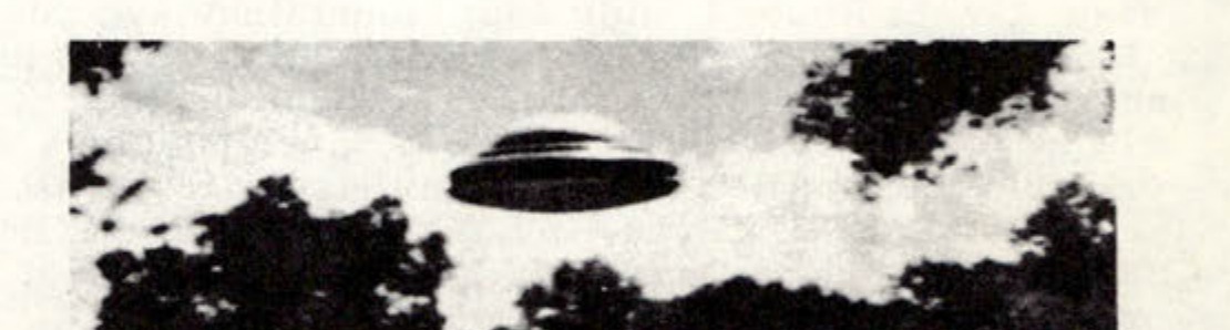 Photograph of a flying saucer over a forested landscape.
