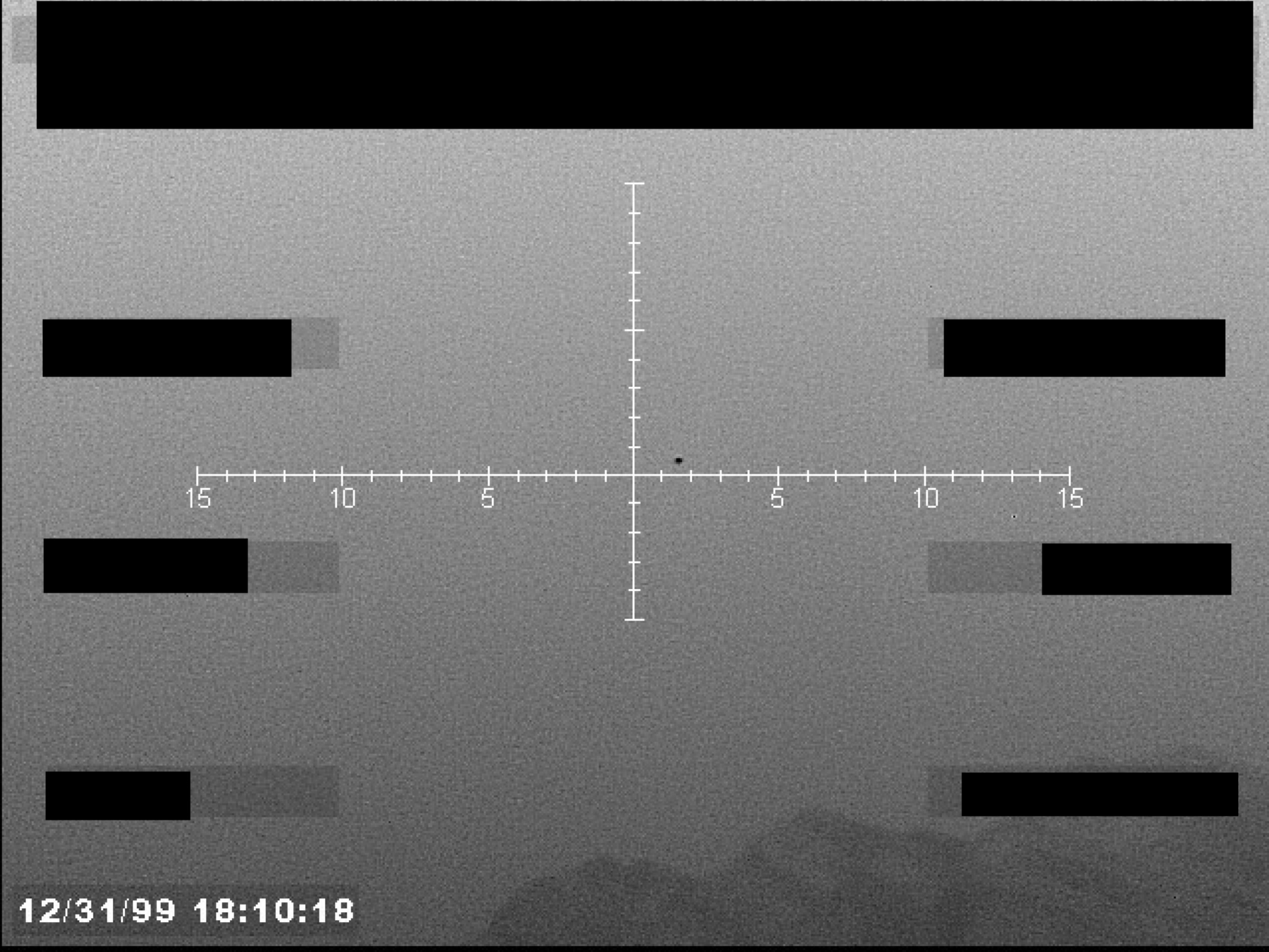 Sensor display, possibly infrared, showing a central crosshair targeting a small, dark, circular object against a grainy background. The display includes horizontal range markings and a timestamp in the lower-left corner.