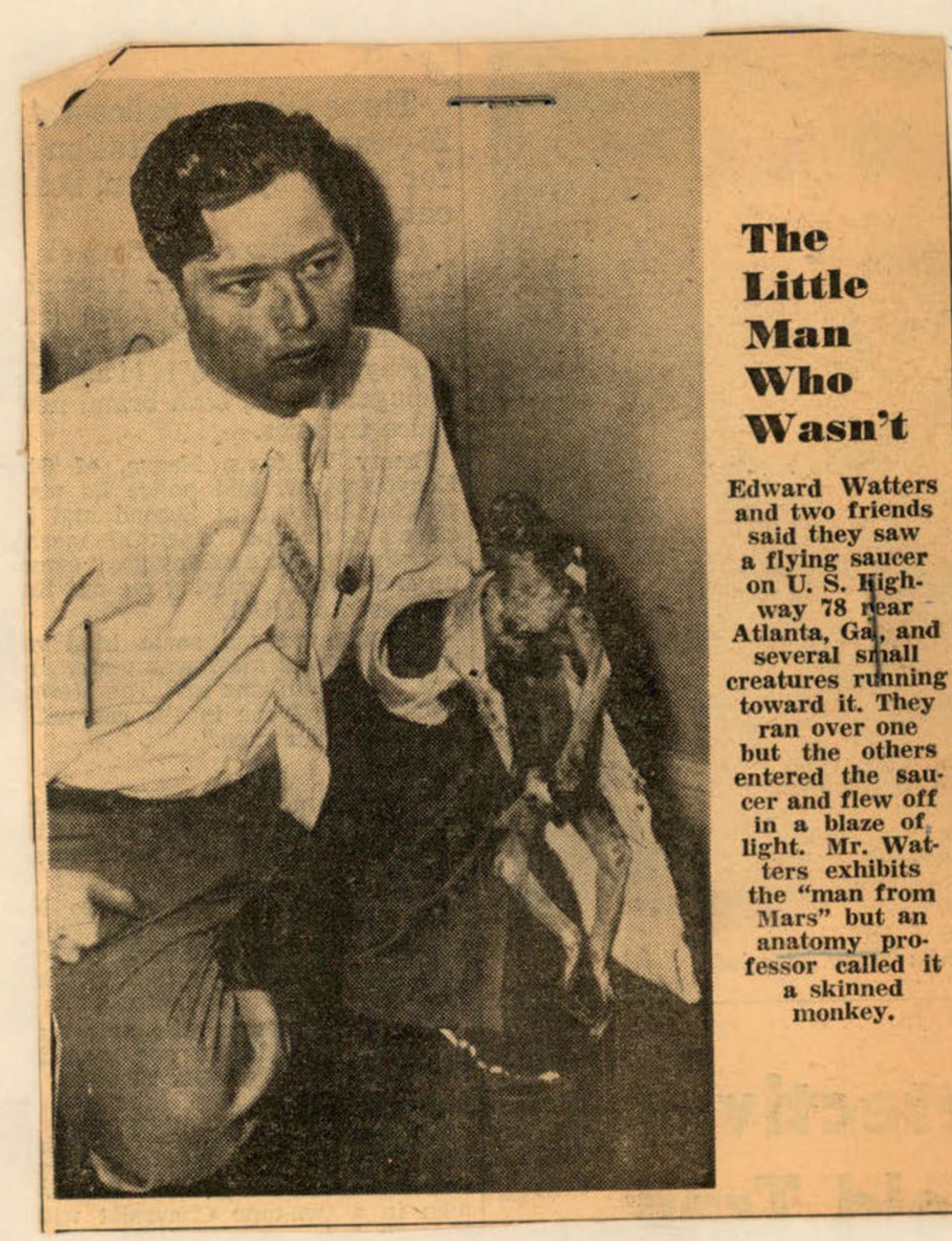 Newspaper clipping with a photo of Edward Watters holding a small, hairless creature, identified as a skinned monkey.